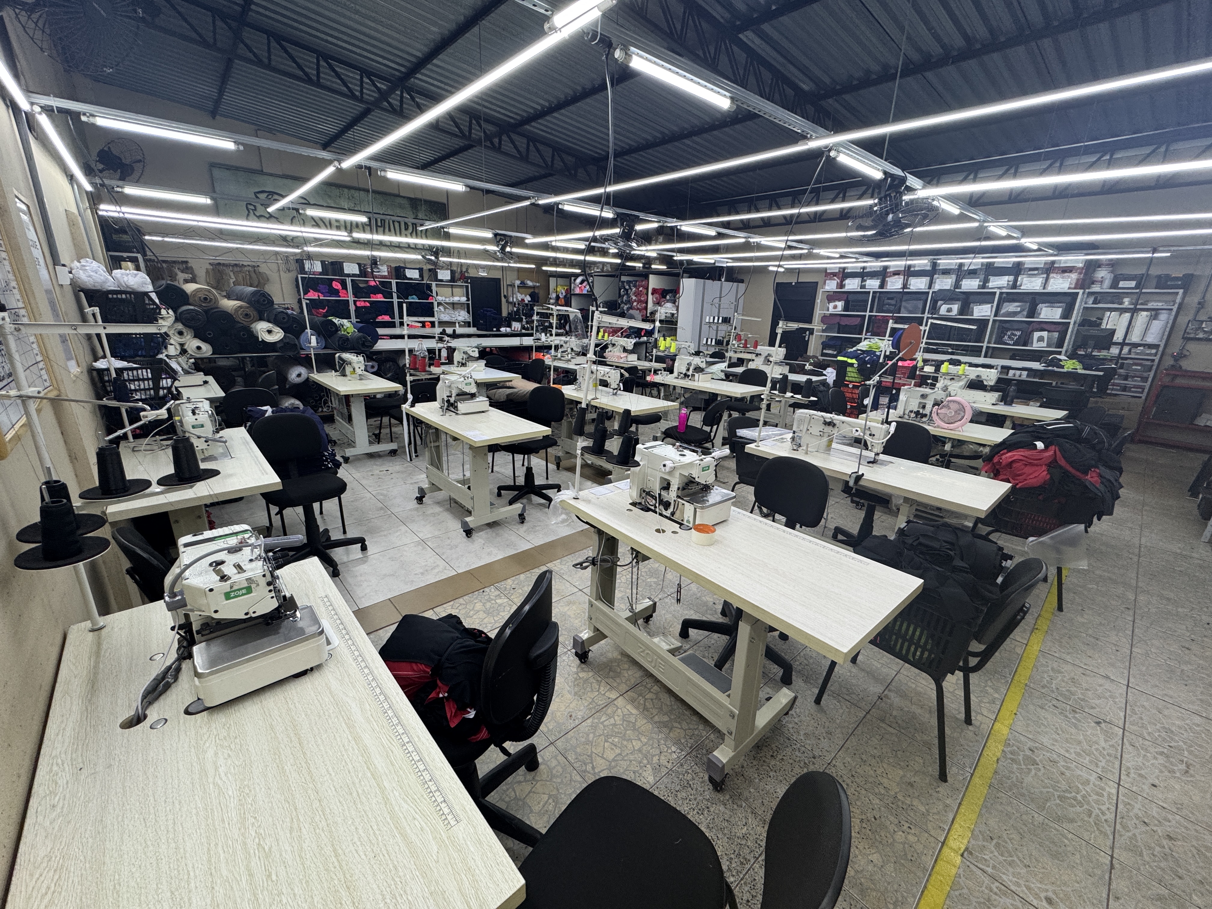 Costureira operando máquina de costura industrial para unir partes de uma camiseta.